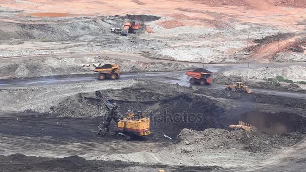 Heavy construction tipper trucks dump coal to the conveyor at coal mine — Stock Video