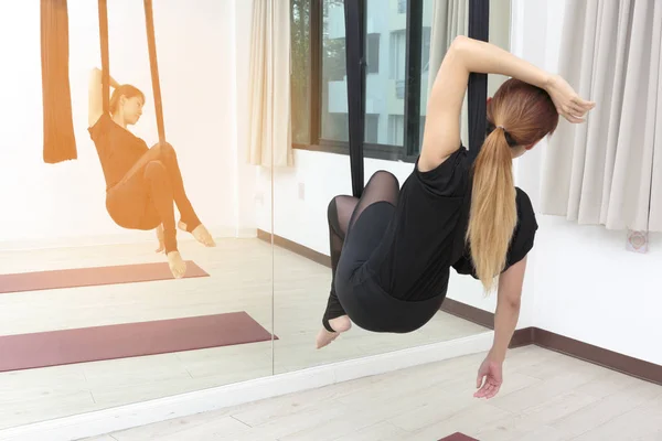 young woman making anti gravity yoga exercises