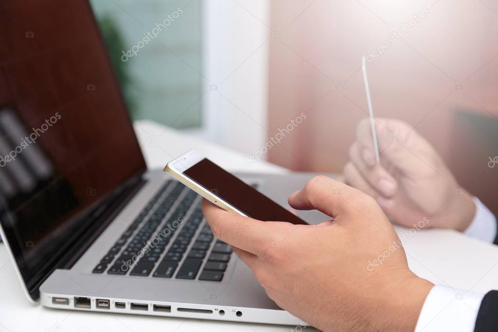 Side view of hands working with laptop and credit card.