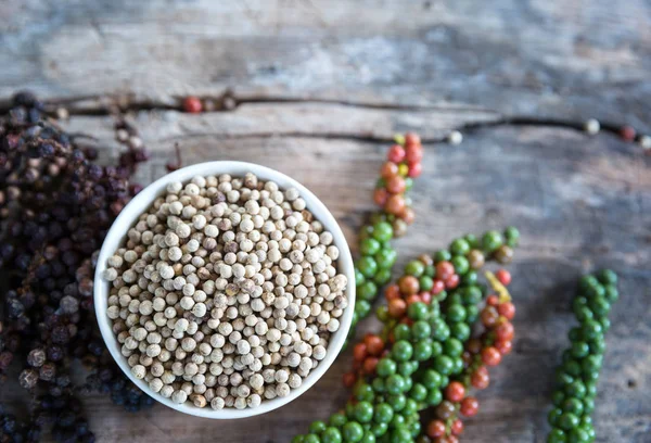 Ingrediensen vitpeppar på cup med gren av svartpeppar och färsk paprika. — Stockfoto