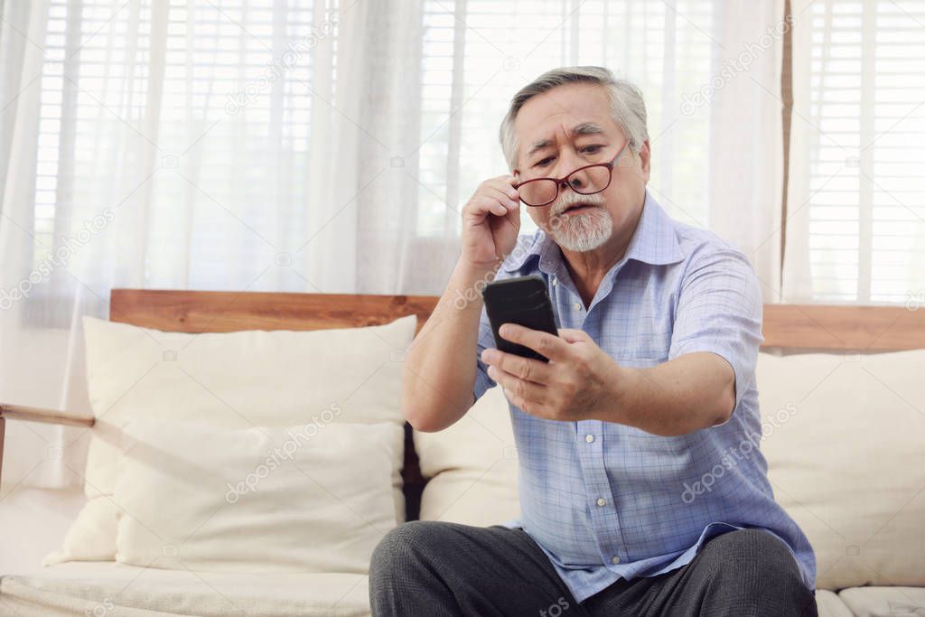 Older men move glasses down to look at the phone in the hand due