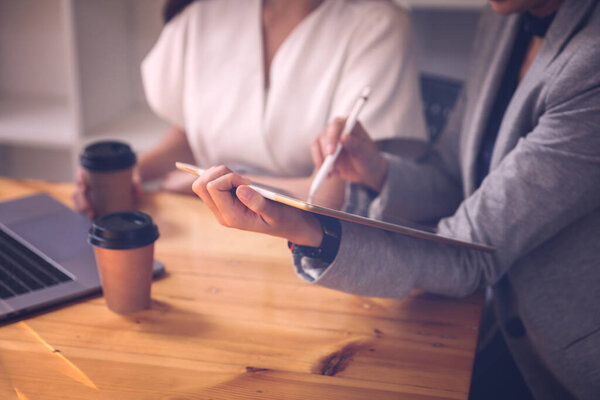 Две деловые женщины обсуждают работу на iPad и пьют кофе вместе, пока работают дома
.
