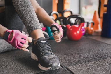 Kettlebell ağırlıklı ayakkabı bağlayan kadın spor salonunda fitness hazırlıyor. Spor salonunda ya da iç mekanda ciğerlere güç katmak için rahat ve sağlıklı bir yaşam sürüyor..