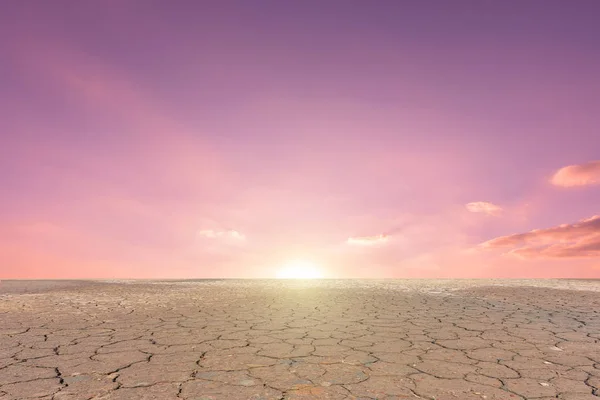 Seca do solo rachado paisagem no pôr do sol céu fundo — Fotografia de Stock