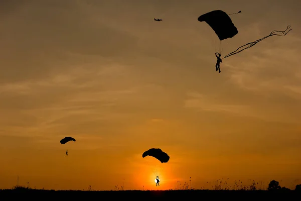 Silhuetten av fallskärm och flygplan på sunset bakgrund — Stockfoto