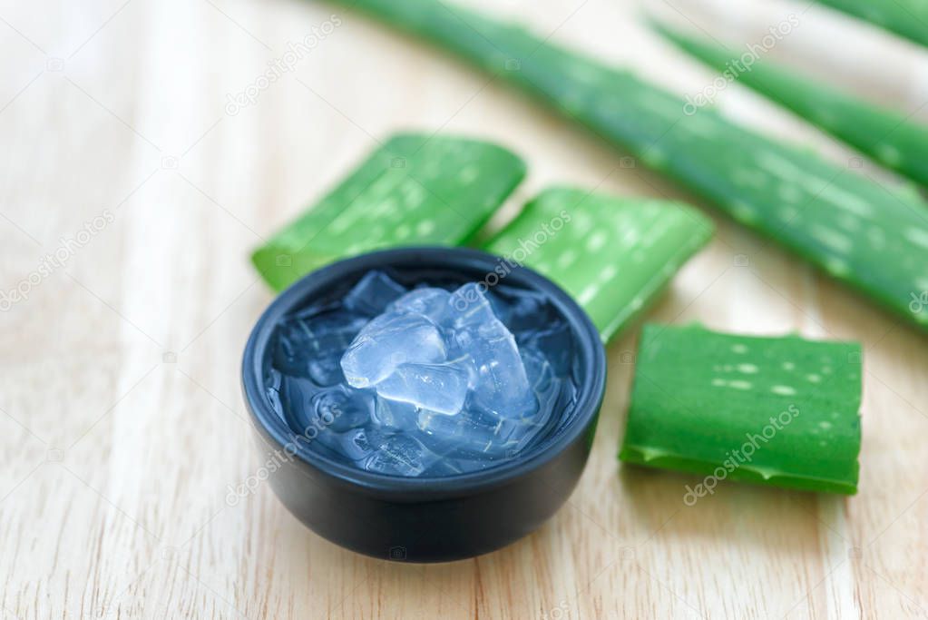 Aloe vera juice in bowl with fresh aloe vera leaves on wooden background