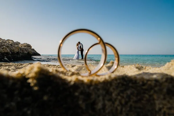 砂の上の大きなリングと水平線の上の小さな恋人 ストック画像