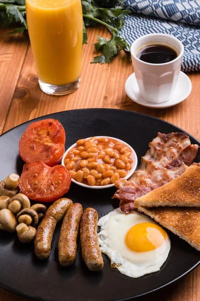 Rustic full english breakfast on black plate — стоковое фото