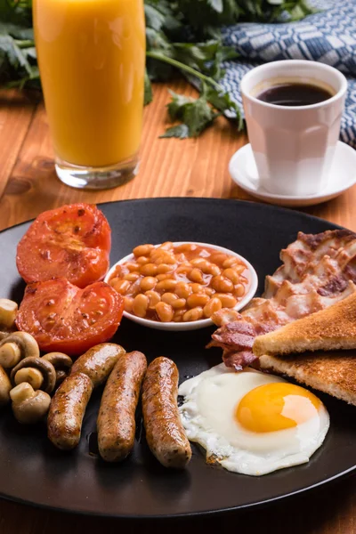 Rustic full english breakfast on black plate — стоковое фото