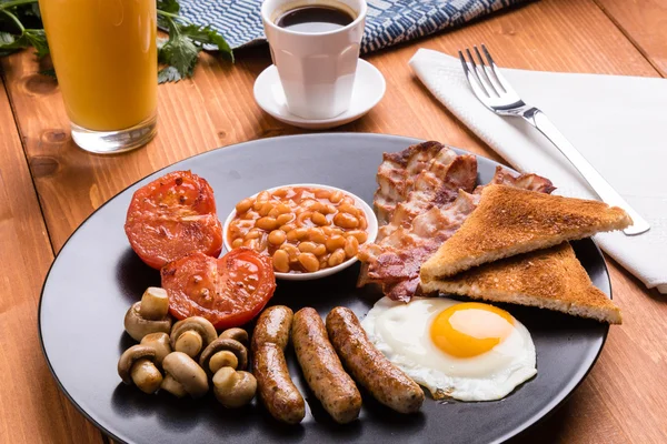 Rustic full english breakfast on black plate — стоковое фото
