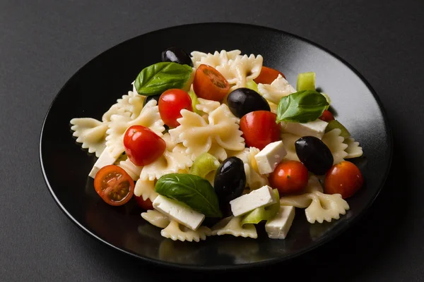 Ensalada de farfalle en plato negro — Foto de Stock