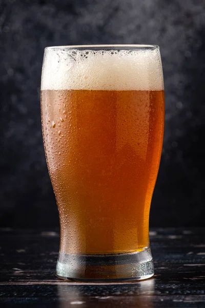 glass of beer on dark background with water droplets