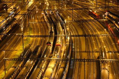 Gece boyunca tren istasyonunun otoparkında bekleyen yük ve yolcu trenlerinin hava görüntüsü.