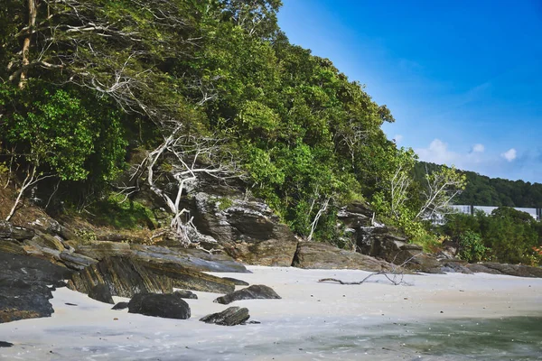Hillside με μαύρα βράχια και πράσινα δέντρα, φυτά στις όχθες της αμμώδους όμορφη εξωτική και εκπληκτική παραλία Cenang στο νησί Langkawi — Φωτογραφία Αρχείου