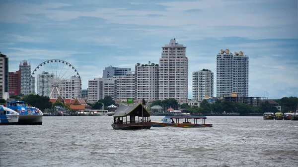 Cityscape view of Bangkok with boats on the Chao Phraya River and with the Asiatique Sky Ferris wheel of the Asiatique The Riverfront large open mall in the background — Stock Photo, Image