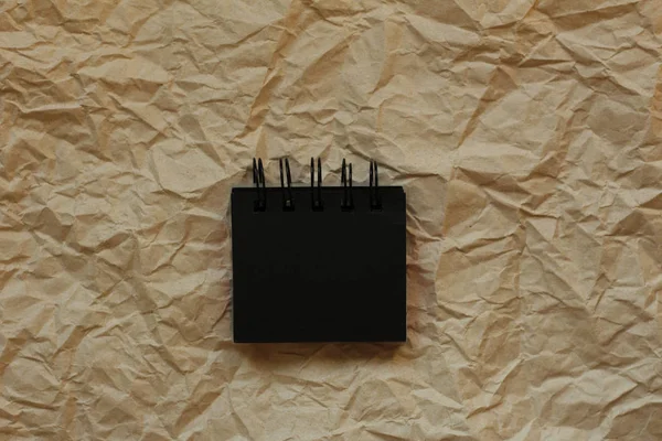 Kırışmış kağıt arkaplanda küçük siyah bir defter. Pankartlar için boşluk kopyala