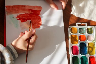 Çocuk elinde fırça ve suluboya ile çizim süreci. Çocuk akvaryumla çiziyor.