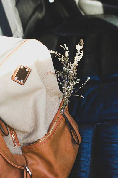 backpack with wild flowers bouquet in the back seat of a car. Romantic adventure concept. Journey and slowliving