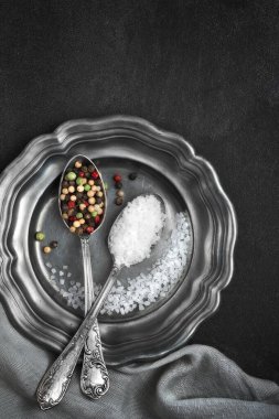 Eski metal plaka üzerinde klasik kaşıklarda karışık biberli tuz koyu gri arka planda keten peçete ve fotokopi alanı