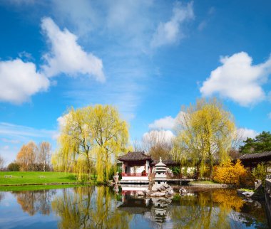 Berlin, Almanya 'da resmi bir Çin bahçesinin göletinde taş tapınak. Modeldeki taş kuleye odaklan.