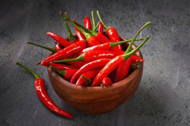 Koyu arkaplanda zeytin ağacından kasede kırmızı acı biberlere yakın çekim. Gıda arkaplanı.