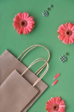 Mercan gerbera papatya çiçekler ve yeşil kağıt arka plan üzerinde zanaat papper alışveriş çantaları, copy-space ile Springtime satış konsept görüntü