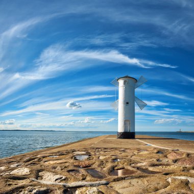 Swinoujscie 'deki eski deniz feneri, Polonya' da Baltık Denizi kıyısında bir liman. Deniz feneri geleneksel bir yel değirmeni olarak tasarlandı. Panoramik kare resim. 