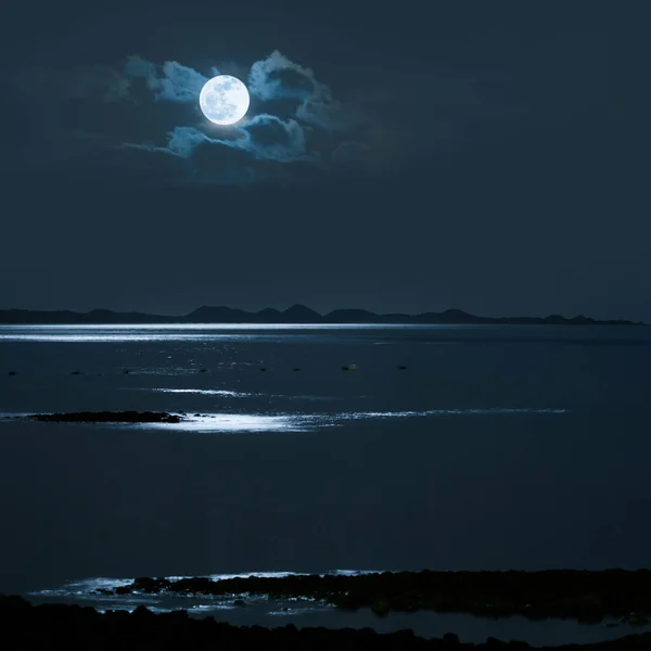 Full Moon over calm sea with a distanc shore