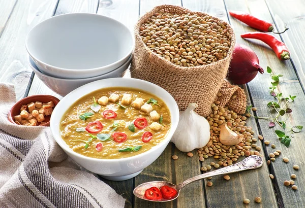 Spicy lentil soup with chili, garlic and onion on rustic wooden table. The soup is served with chili, croutons and thyme leaves. — Stock Image Spicy Lentil Soup Chili Garlic Onion Rustic Wooden Table Soup Stock Photo