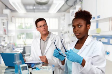 Bilim adamları, beyaz erkek ve Afrikalı kadın, laboratuvarda çalışıyorlar.
