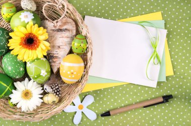 Paskalya çerçevesi, yumurtalar, çiçekler ve sahte kimliklerle, mesajınız için bir kağıt kartla.. 