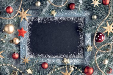 Boş tahtası olan yeşil ve altın rengi Noel arkaplanı. Köy tahtasında karla süslenmiş tebeşir dalları. Kopyalama alanı olan üst görünüm.