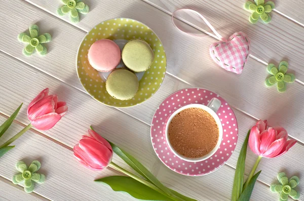 Spring coffee background. Macarons, espresso in pink cup, freesias and pink tulips, top view.