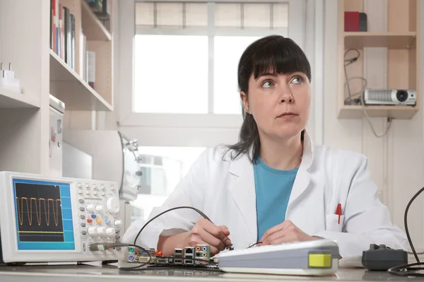 Young female tech or engineer repairs electronic equipment