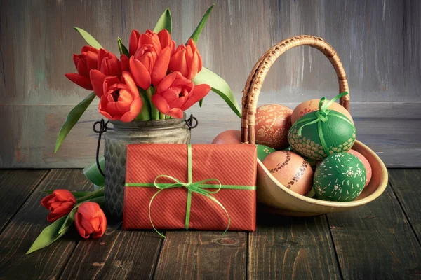 Naturaleza muerta de Pascua. Tulipanes rojos y una cesta de rojo y verde Oriente — Foto de Stock
