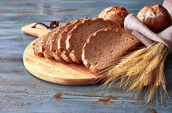 Хлеб из цельнозернового хлеба, нарезанный на борту булочками рзе и золотым колосом — стоковое фото