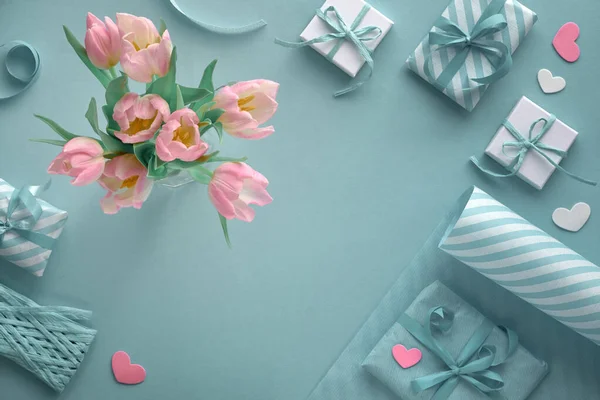 Blauwe achtergrond met roze tulpen, gestreept inpakpapier en cadeaupapier — Stockfoto