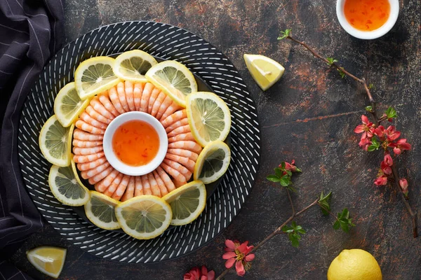 Crevettes zestées au citron et à l'ail servies dans une assiette sombre avec des citrons — Photo