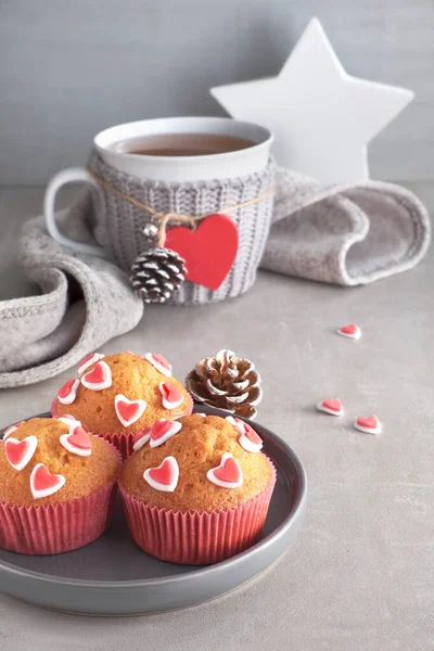 Muffins decorated with sugar hearts and a cup with red heart on — Stock Photo, Image