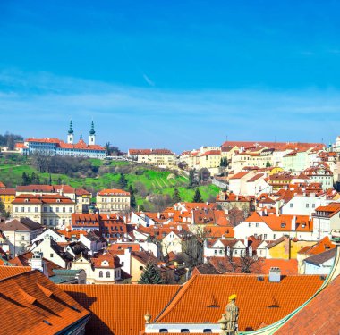 Turuncu eski tepe üzerinde Prag Strahov Manastırı ile çatılar. Mavi gökyüzü üzerinde metin için yer.