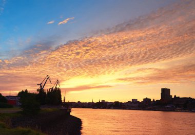 Almanya 'da gün batımında Hamburg Limanı. Nakliye vinçleri.