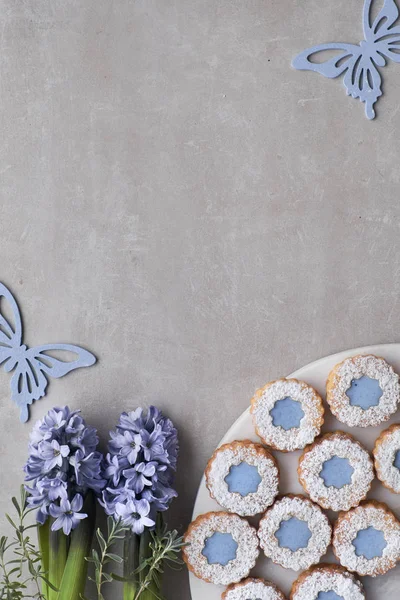 花林泽饼干与蓝色玻璃在光混凝土背景装饰与蓝色葫芦花和蝴蝶 带复制空间的顶视图 — 图库照片