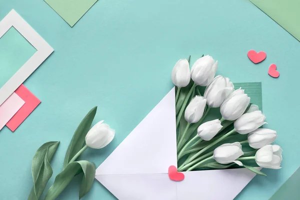 カードや装飾的な心と青のミントの背景に紙の封筒で白いチューリップ コピースペースでGeometris春の背景 — ストック写真