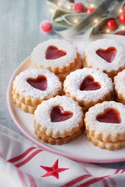 Geleneksel Noel Linzer kurabiyelerine yakın plan. Çilek reçeli ve Noel süslemeleriyle dolu.