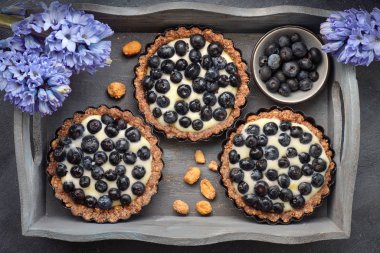 Koyu arkaplanda vanilyalı yaban mersinli tartların üst görüntüsü