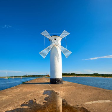 Swinoujscie 'deki eski deniz feneri, Polonya' da Baltık Denizi kıyısında bir liman. Deniz feneri geleneksel bir yel değirmeni olarak tasarlandı. Kare panoramik resim. 