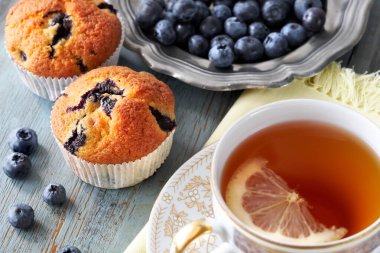 Gri rustik ahşap masada limon ile yaban mersinli muffin ve çay fincan yakın çekim