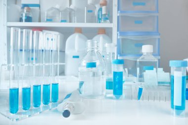 Araştırma laboratuarının içiyle mavi-beyaz bilimsel arka plan. Cam tüplerdeki mavi protein örnekleri, tamponlar ve çeşitli testler için kimyasal tozlar. Biyoloji metodolojisini resimlemek için arkaplan