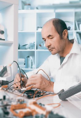 Kıdemli erkek teknik elektronik cihaz servis merkezinde sınar.