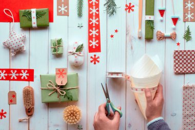 Çeşitli Noel ya da yeni yıl tatilleri doğal dekorasyonlar, el işi kağıt paketler ve çevre dostu sıfır atık hediyeler. Tahtaya uzanmış, elleri koni şeklinde şerit ve yemyeşil süslemiş..